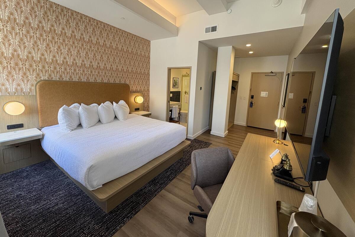 Une chambre d’hôtel avec un grand lit, un bureau avec un ordinateur, une chaise et un miroir.