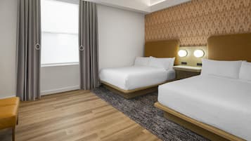 Ein Hotelzimmer mit zwei Betten, einem Fenster mit Vorhängen, einer Wand mit Muster und einem Holzboden.