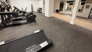 A gym with treadmills, stationary bikes, and a mirrored wall.