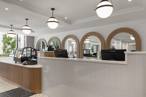 Una moderna zona de recepción con mostrador, varias estaciones de trabajo con computadoras y una máquina de café.