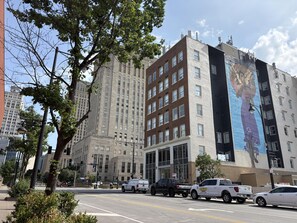 A multi-story building with a large mural on the side, a street with cars, and trees in the foreground. - Aiden By Best Western Kansas City Downtown (Kansas City)
