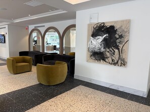 A lobby with modern furniture, a large abstract painting, and a view of the street through arched windows. - Aiden By Best Western Kansas City Downtown (Kansas City)