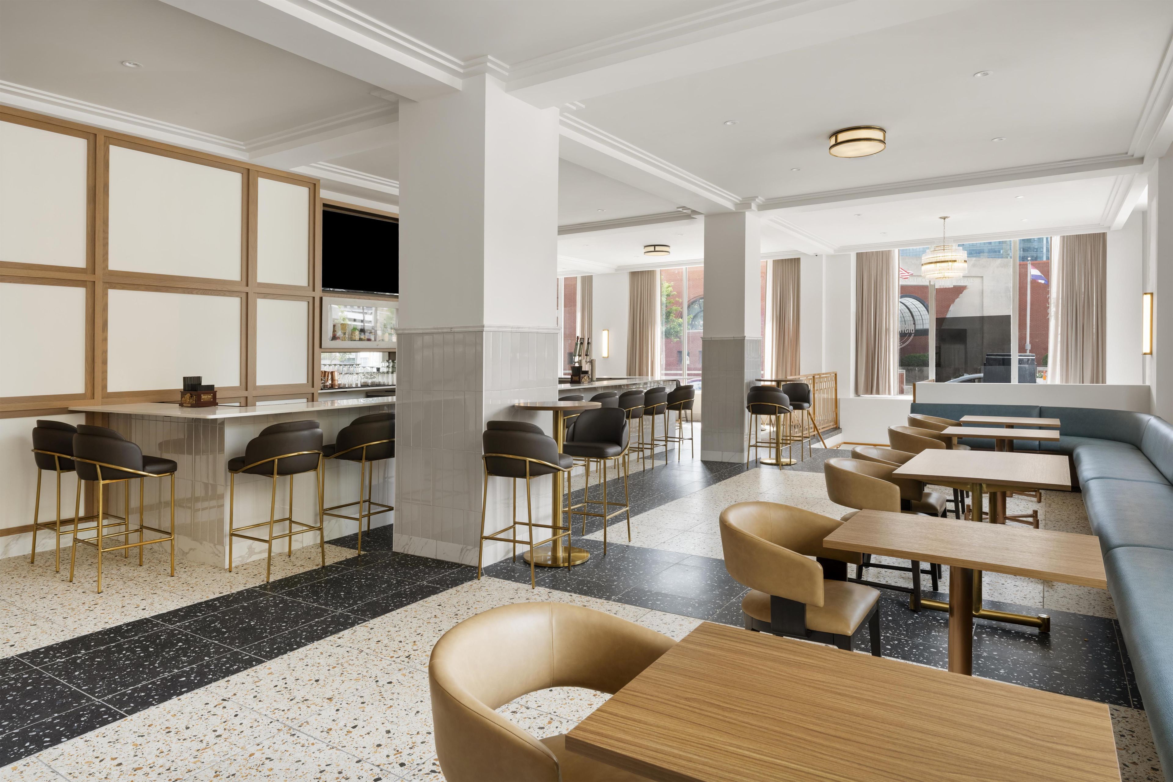 A modern interior with a bar area, seating, and large windows.