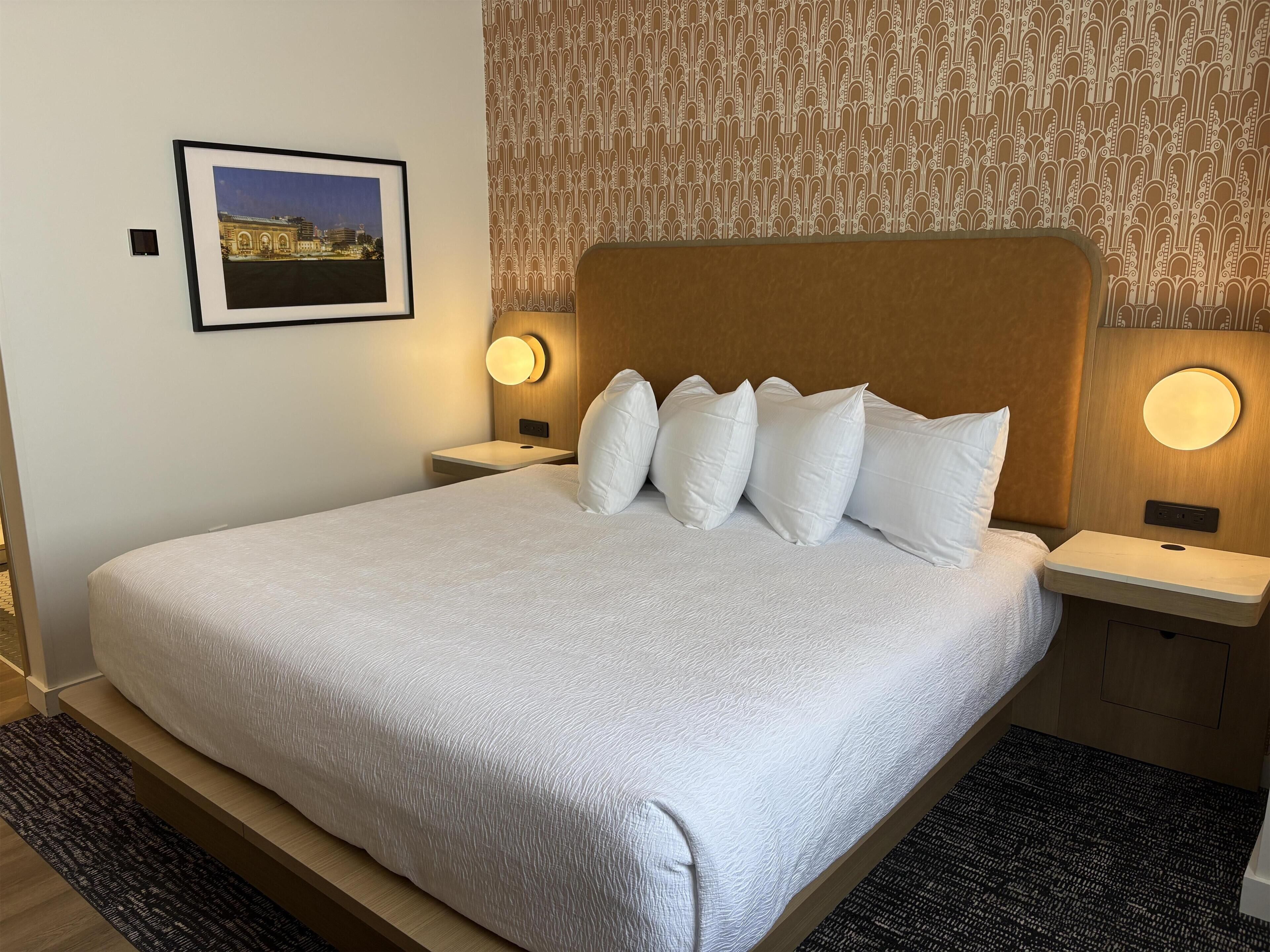 A neatly made bed with white linens, a headboard, and two bedside lamps.