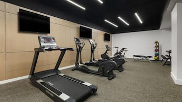 A gym with treadmills, elliptical machines, and a bench press.