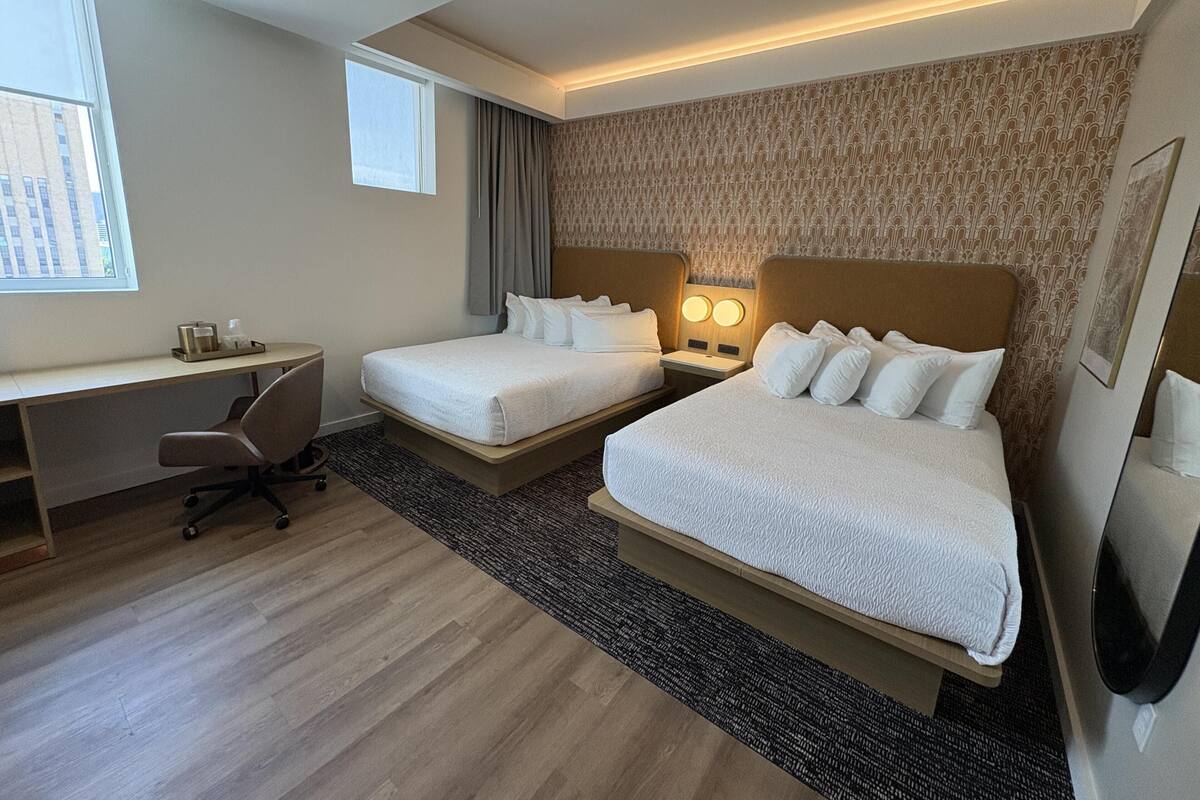 Une chambre d’hôtel avec deux lits, un bureau et une chaise.