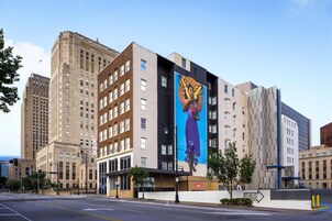 A hotel with a large mural on the side, a modern building facade, and a clear sky.