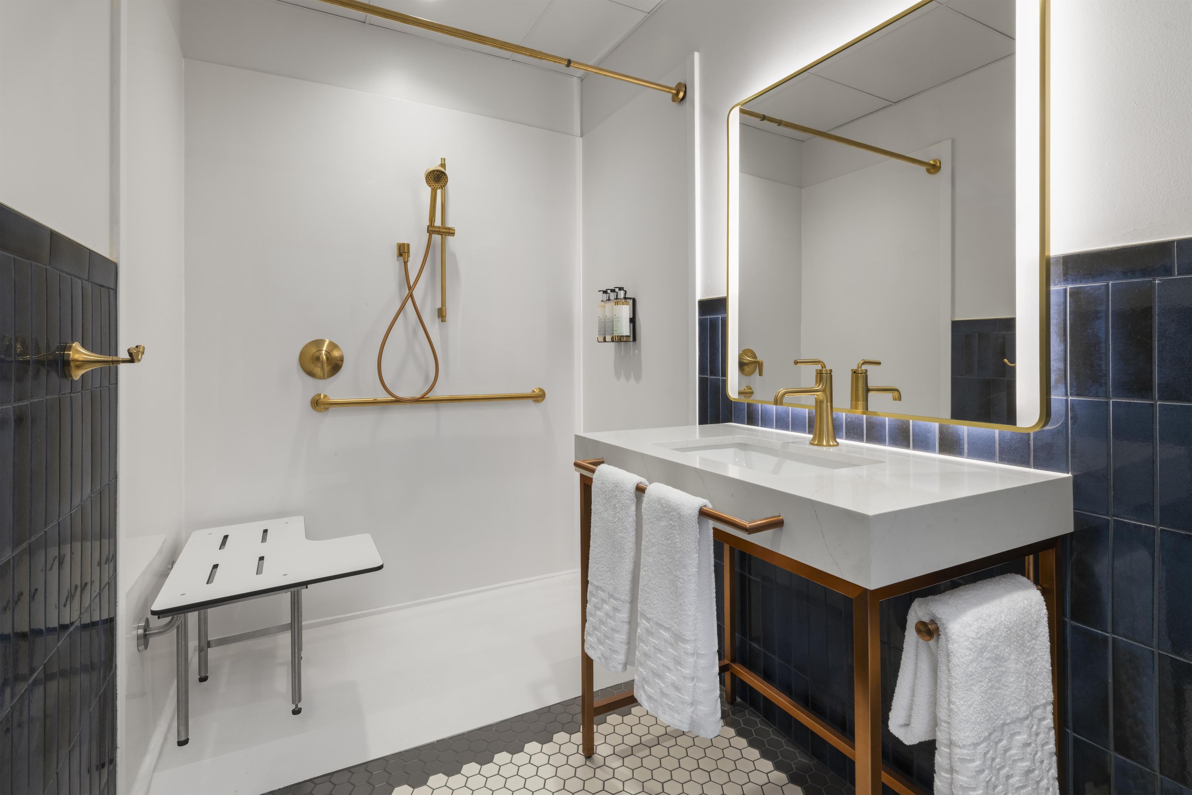 A modern bathroom with a white sink, gold fixtures, and a large mirror.