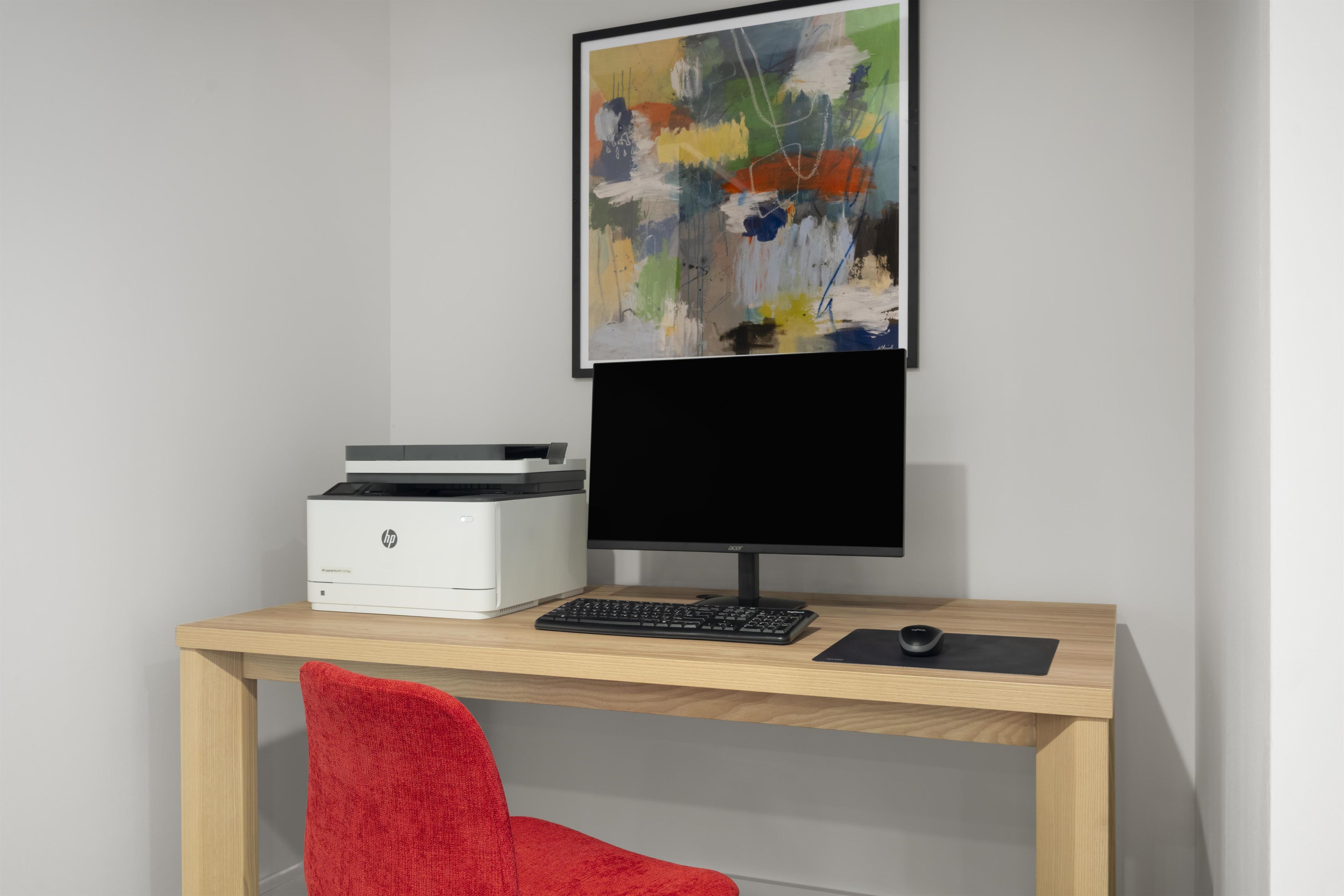 A modern office desk with a printer, keyboard, and monitor.