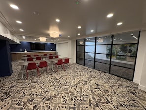 A conference room with a patterned carpet, red chairs, a long table, a large screen, and a view through a glass wall. - Aiden By Best Western Kansas City Downtown (Kansas City)