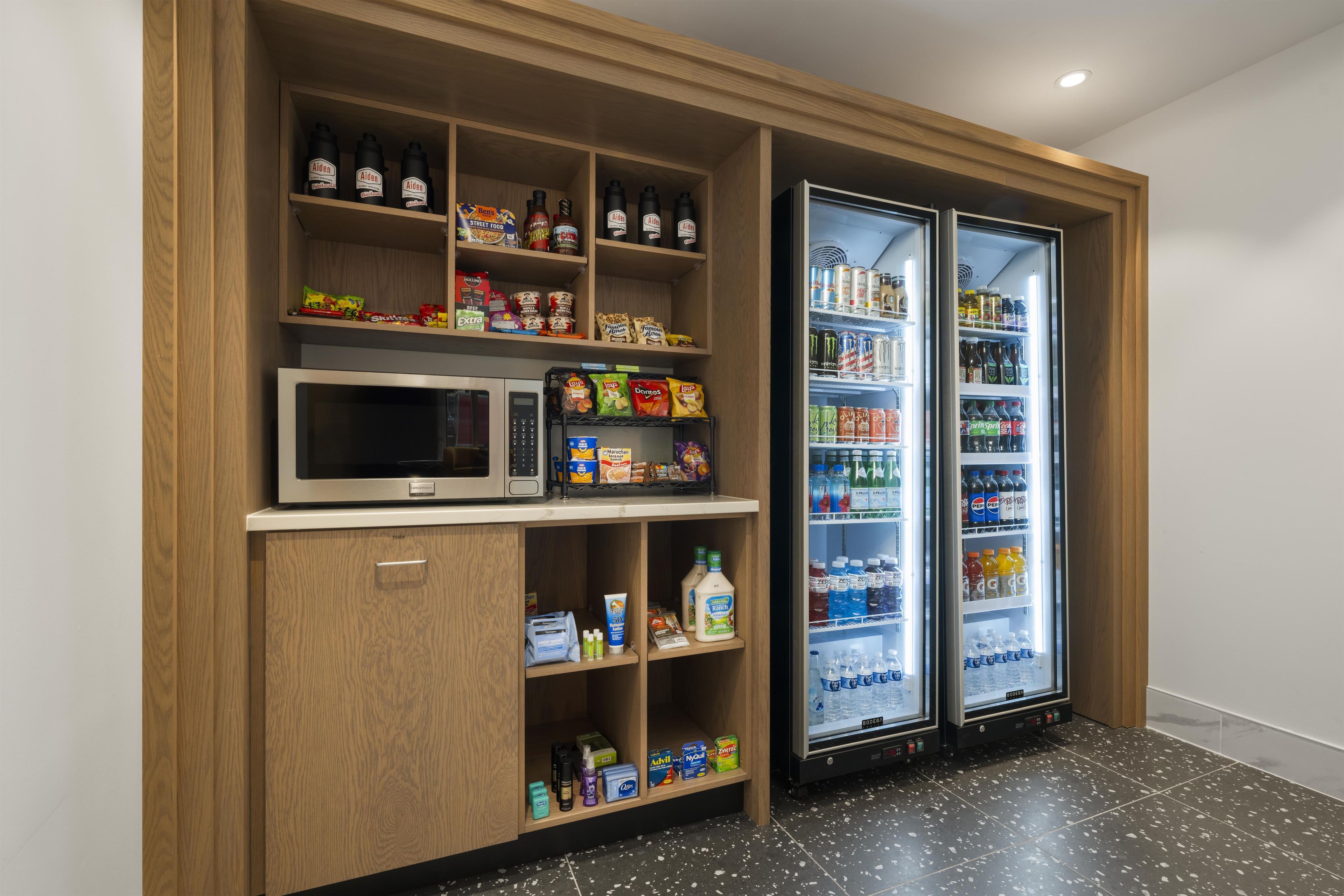 A kitchenette with a microwave, shelves stocked with snacks, and a refrigerator with beverages.