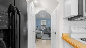 Una cocina moderna con un refrigerador negro, armarios blancos y una encimera de madera.