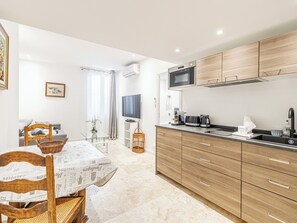 A modern kitchen with wooden cabinets, a built-in microwave, and a coffee maker. - Charming 1-bedroom apartment 200m from the Palais (Cannes)