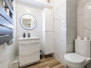 A modern bathroom with a marble vanity, a toilet, and a mirror with a light. - City-center apartment 100m from the Croisette (cannes)