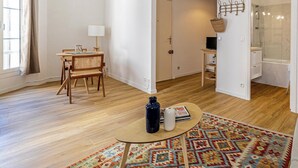 Una sala de estar moderna con piso de madera, una mesa redonda de centro, un sofá y un tapete estampado.