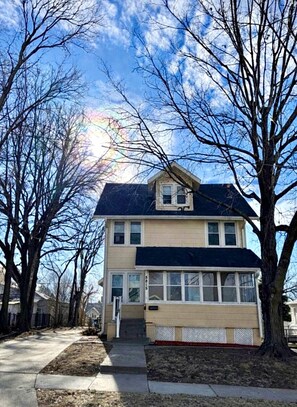 A two-story house with a gabled roof, a front porch, and a visible address number. - Cozy Duplex in the Heart of Benson (Omaha)