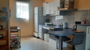 A compact kitchen with a dining table, cabinets, and a small refrigerator. - "Le Pesquit" large, fully-equipped 36m2 studio on one level: private terrace. (Lescar)