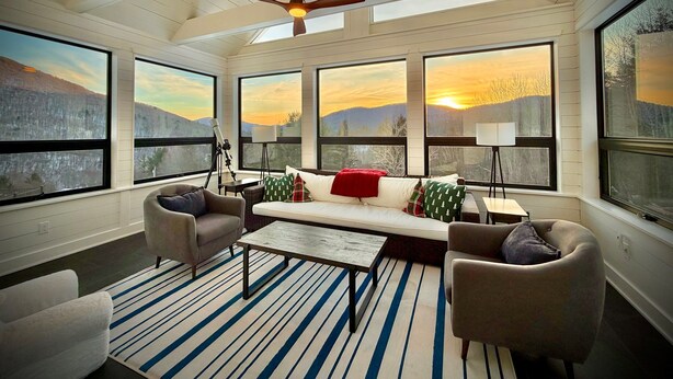 Ein gemütliches Zimmer mit großem Fenster, Deckenventilator und Bergblick.