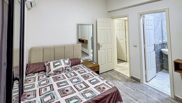 Una camera da letto con un letto, un armadio, uno specchio e una porta che dà su un bagno.