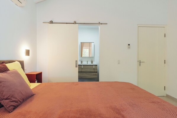A bedroom with a bed, a nightstand, a dresser, a mirror, and a door. - Modern 3 bedroom villa with private pool at gated Coral Estate Beach Resort (Sint Willibrordus)