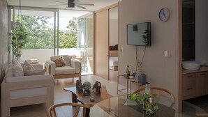 Ein modernes Wohnzimmer mit einem Glastisch, einer Couch und einem an der Wand befestigten Fernseher.