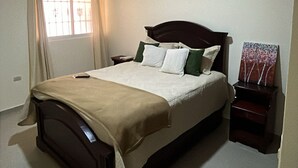 A bedroom with a bed, bedside table, and an air conditioning unit. - Gateway to the Caribbean: Perfect Getaway in Puerto Plata (Puerto Plata)