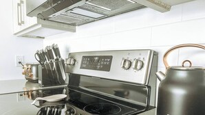Cozinha com fogão de aço inoxidável, chaleira e porta-facas.