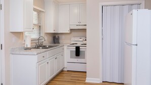 Una cocina moderna con armarios blancos, un lavamanos de acero inoxidable y un horno empotrado.