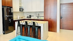 Eine moderne Küche mit Kochinsel, Barhocker, Kühlschrank und Mikrowelle.