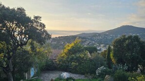 A wooden deck with a swimming pool, surrounded by trees and a view of a town and hills in the distance. - Le Clos Ferté villa in Le Lavandou (Le Lavandou)
