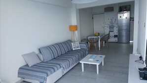 Un salon moderne comprenant un canapé, une table basse et un coin repas avec des chaises.