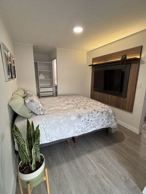 A bedroom with a bed, a TV mounted on the wall, a potted plant, and a closet. - 2-bedroom apartment w/Pool in Miraflores close to Larcomar (Miraflores)