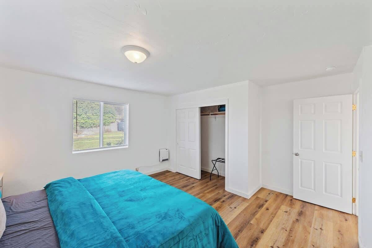 A bedroom with a bed, a window, a closet, and a door.