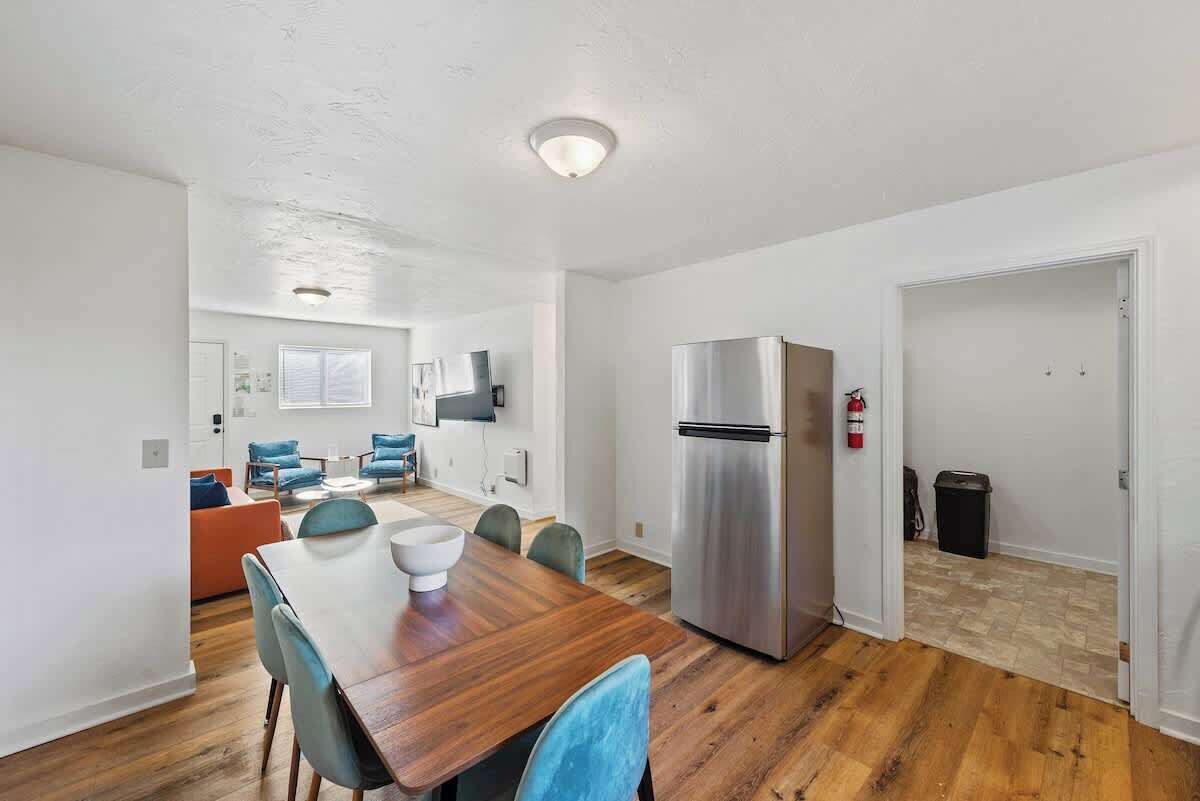 Et moderne køkken med et stålkøleskab, et spisebord med stole og en opholdsstue med sofa og stole.