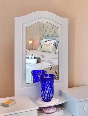 Ein Schlafzimmer mit einem Spiegelkleiderschrank, einem Nachttisch mit einer blauen Vase und einem Beistelltisch mit einer kleinen Ablage.