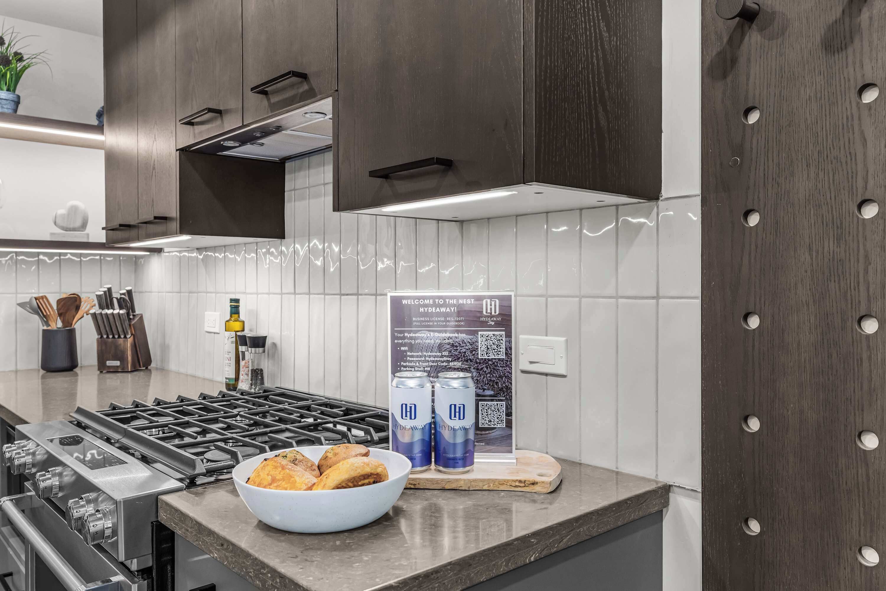 A modern kitchen with a gas stove, a bowl of food, and two cans of beer on the counter.