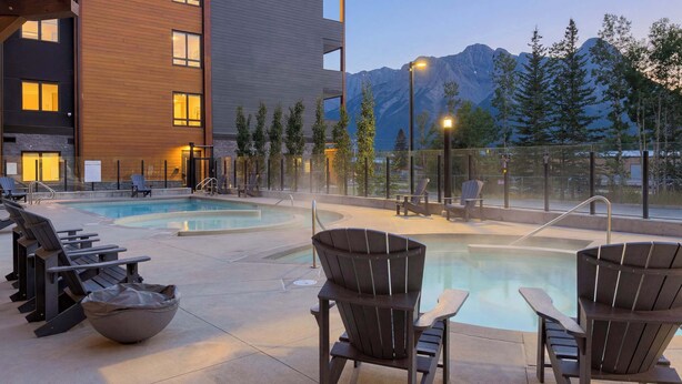 Un espace piscine avec des chaises longues et une vue sur les montagnes.