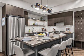 Una cocina moderna con un refrigerador de acero inoxidable, una isla central con taburetes de bar y muebles de madera.