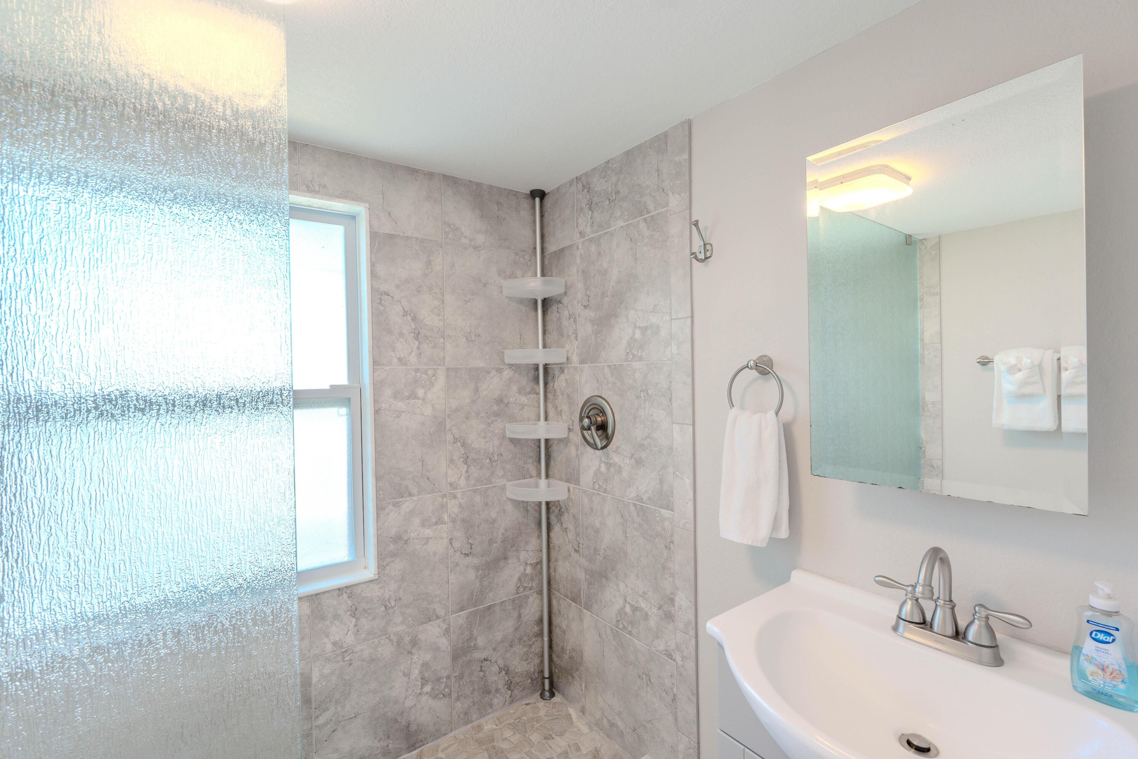 Un baño moderno con ducha, lavamanos y espejo.