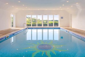Ein Hallenbad mit Sonnendesign im Boden, großen Fenstern und einem Schild mit der Aufschrift 1,2m.