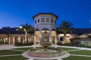 A courtyard with a central fountain, a tower structure, and palm trees. - Pet Friendly Family Resort Townhome with Private Pool • Lazy River • Near Disney (Davenport)
