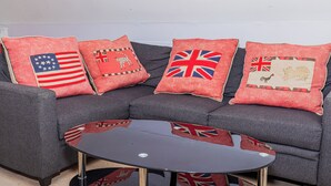 Un sofá gris con cuatro almohadones, cada uno con la bandera de un país diferente.