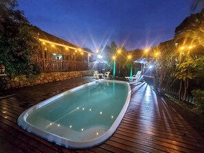 Una piscina al aire libre, sombrillas, sillones reclinables de piscina