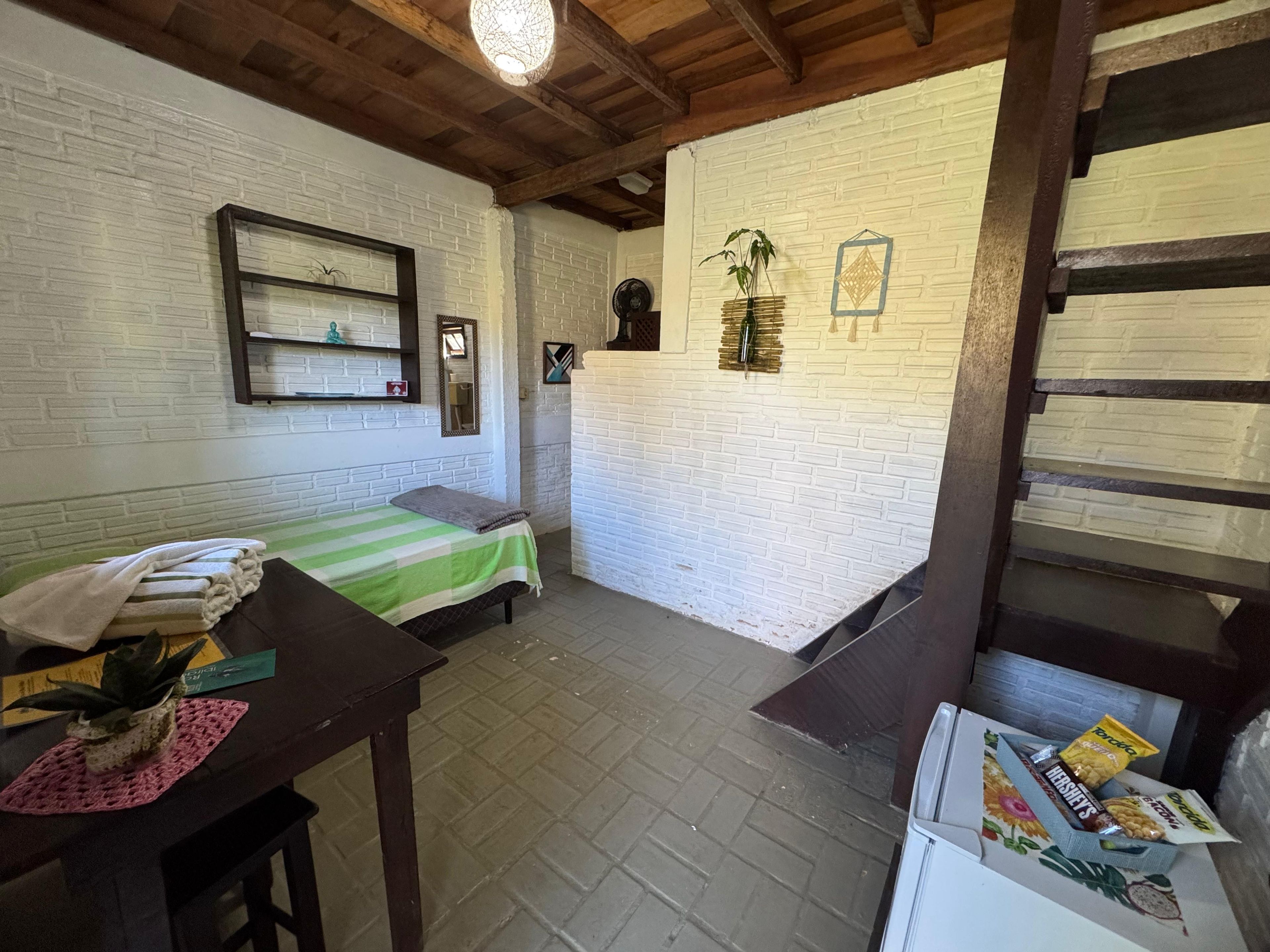 Una habitación con cama, una mesa con planta, un espejo y una pared con diseño de ladrillo.
