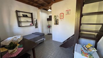 Una habitación con una cama, un escritorio con una planta, un ventilador y una escalera.