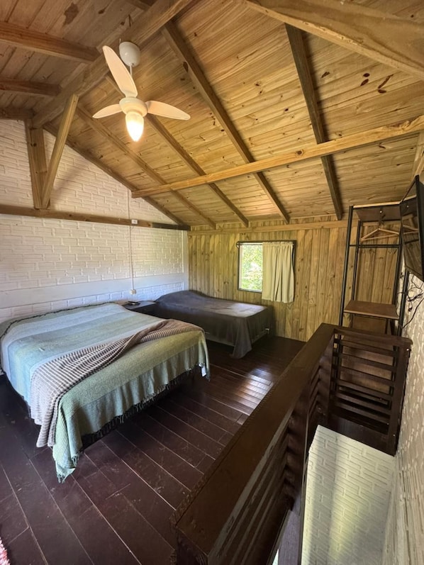 A room with two beds, a wooden ceiling, a window with curtains, and a staircase. - Pousada Vale da Praia (Imbituba)