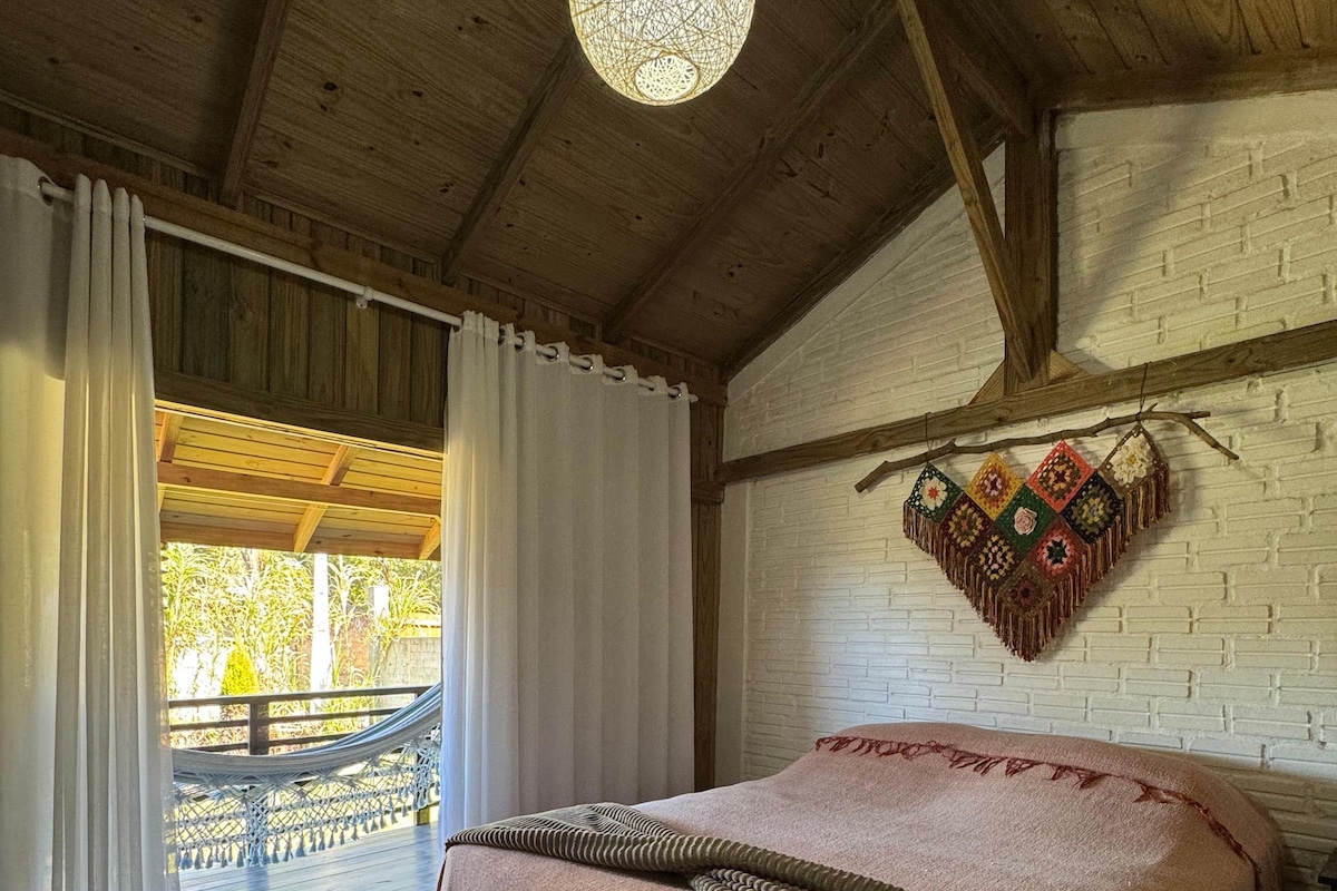 Un dormitorio con techo de madera, una cama con colcha estampada, un colcha colgante y vistas al exterior.