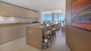 Een moderne keuken met een centraal eiland, barstoelen en uitzicht op de stad.