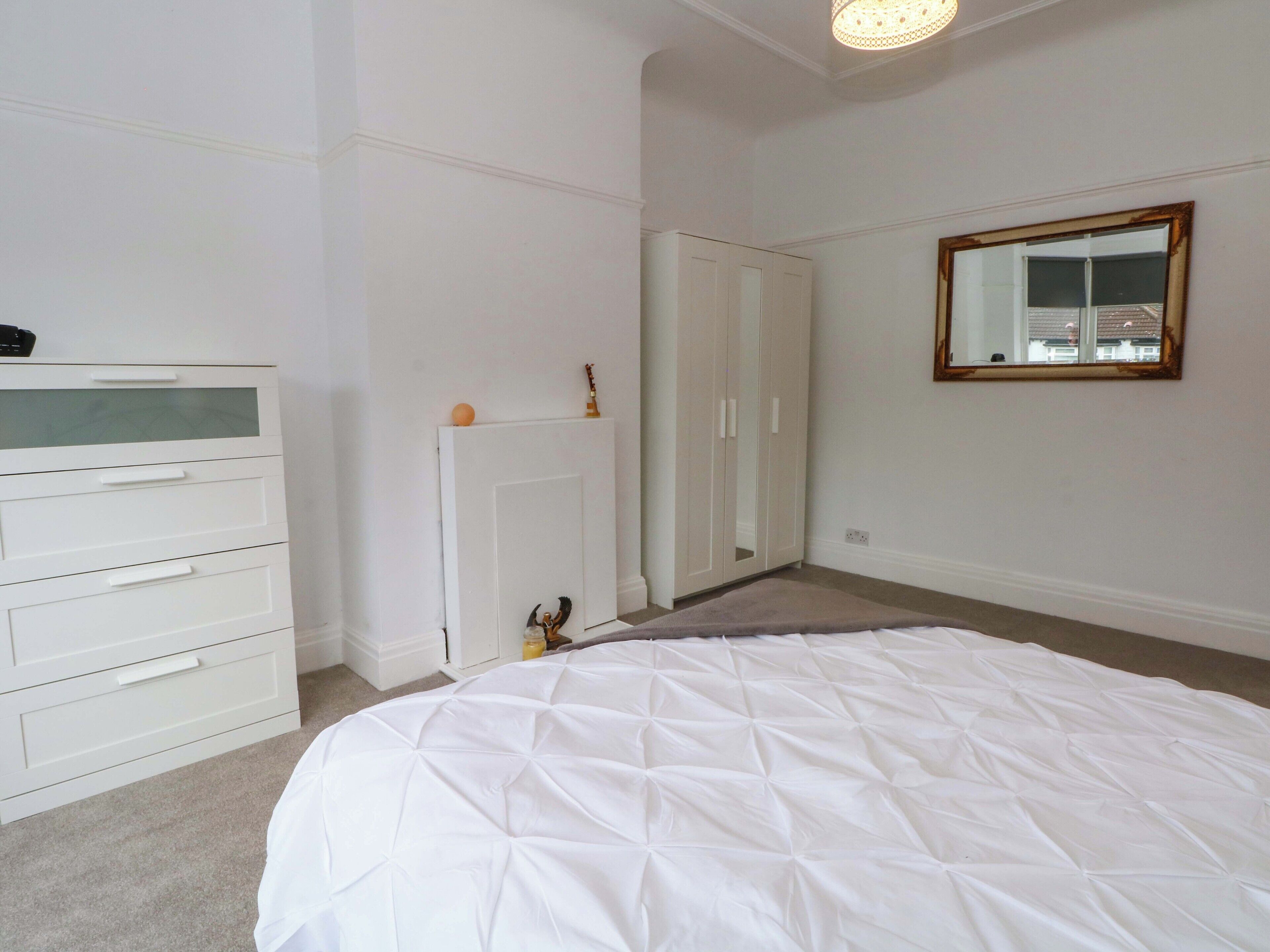 Un dormitorio con cama, cómoda, armario y espejo en la pared.