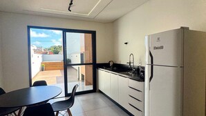 A modern kitchen with a dining area, featuring a large window, a refrigerator, and a sink. - Sobrado 03 (Florianópolis)